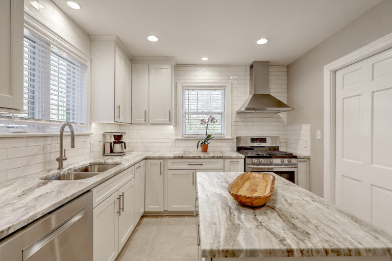 A modern kitchen designed and built by Citadel Enterprises, featuring sleek gray and white cabinetry, state-of-the-art appliances, and ample natural light, creating a clean, contemporary, and inviting cooking and dining space.