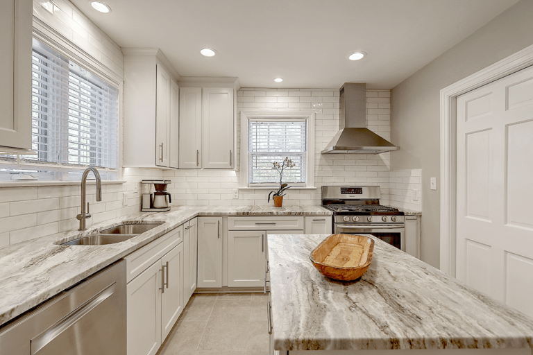 A modern kitchen designed and built by Citadel Enterprises, featuring sleek gray and white cabinetry, state-of-the-art appliances, and ample natural light, creating a clean, contemporary, and inviting cooking and dining space.