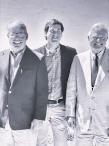 Three generations of the Loy family, founders and leaders of Citadel Enterprises Remodeling, smiling together in professional attire, showcasing their legacy in luxury home renovations.