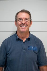 Kelley Browning, Production Coordinator at Citadel Enterprises, smiling in a blue polo shirt against a light wood panel background.