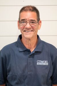 Matt A, Project Manager and Lead Carpenter at Citadel Enterprises, smiling in a blue polo shirt with company logo, against a light-colored background.